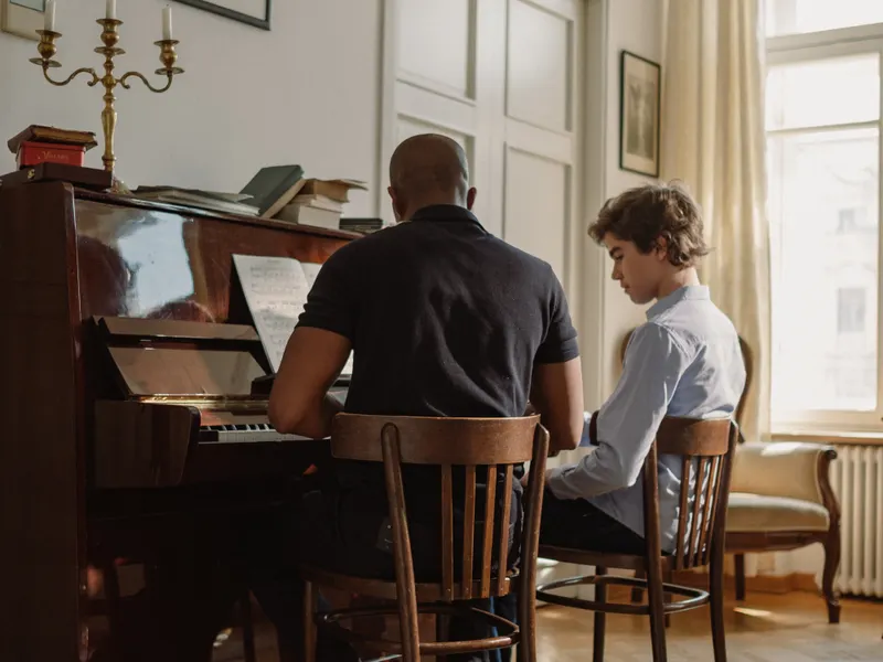 Profesor de piano dando clase a un alumno